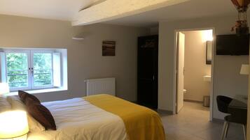 A bedroom with a bed, a window, a radiator, a wardrobe, and a television.