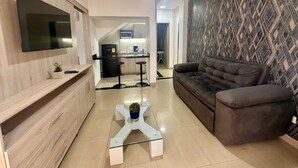 Una sala de estar moderna con un televisor de pantalla plana, un sofá y una mesa de centro con una planta.