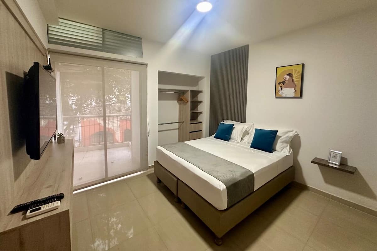A modern bedroom with a bed, a TV, a sliding door, and a small shelf.