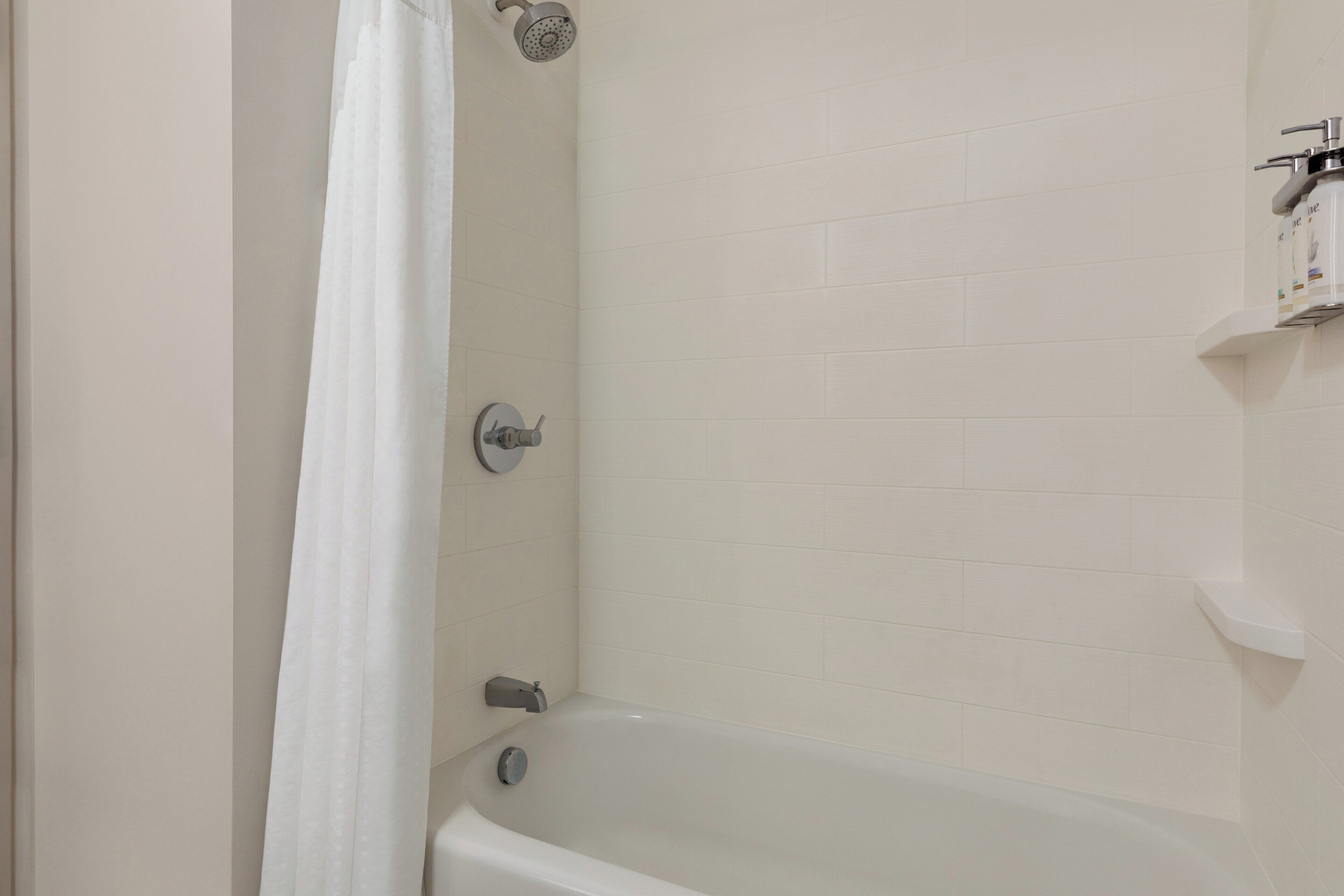 A bathroom with a bathtub, a showerhead, and a toilet.