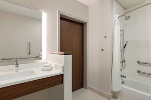 A modern bathroom with a large mirror, a sink with a wooden vanity, a shower with a glass door, and a door with a handle. - Holiday Inn Express & Suites Dalton - Walnut Ave by IHG (Dalton)