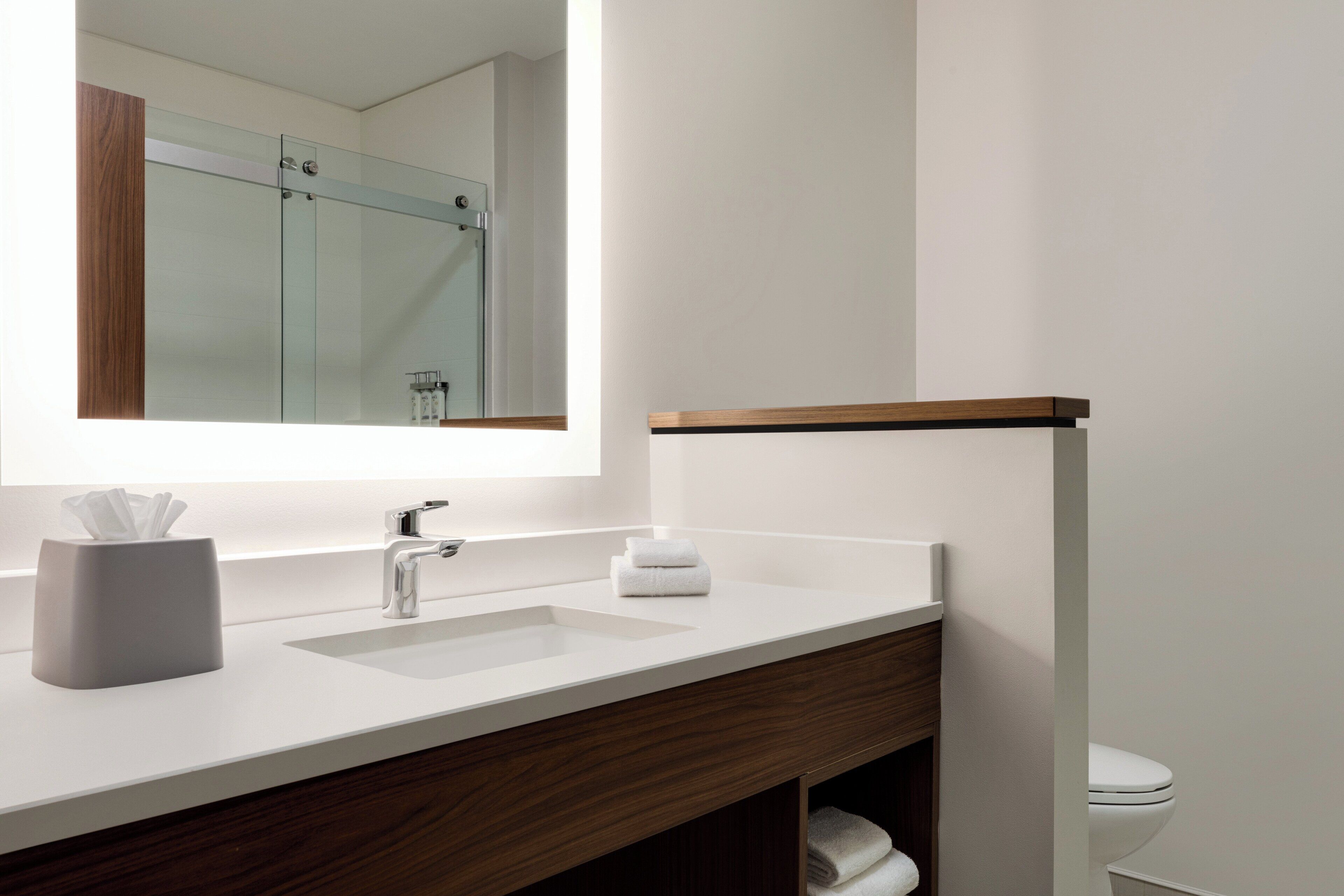 A modern bathroom with a white sink, a mirror, and a glass shower enclosure.