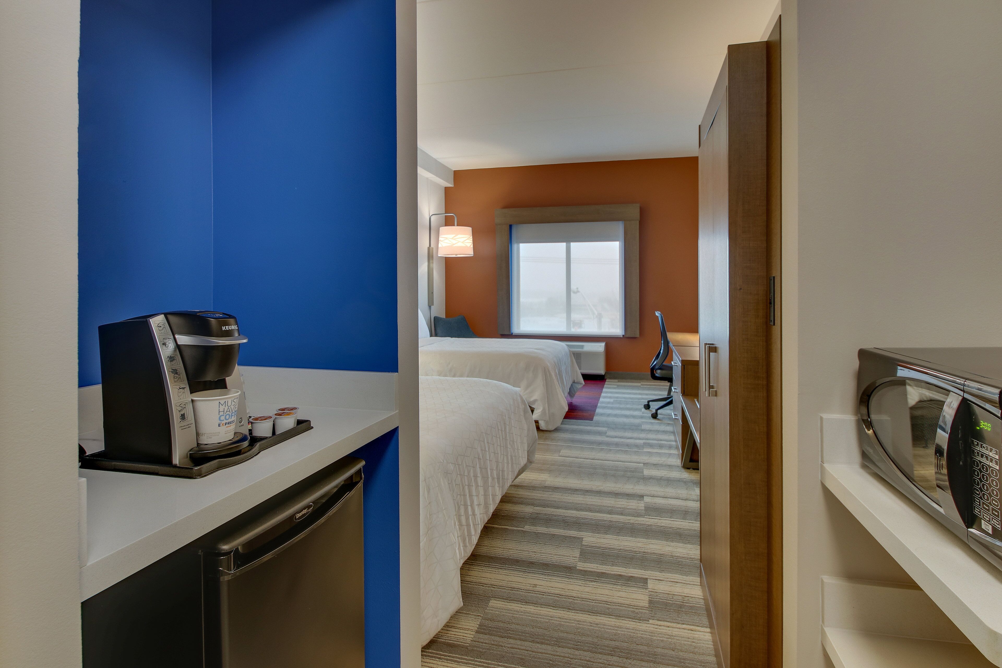 Habitación de hotel con kitchenette, una cama, un ventanal y microondas.