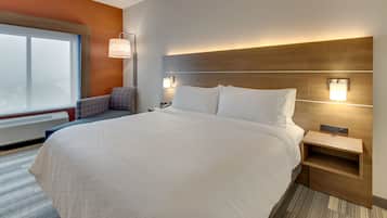 Habitación de hotel moderna con una cama grande, una mesita de noche, una lámpara de pared y un ventanal con vistas.