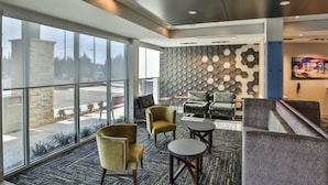 A modern hotel lobby with large windows, a geometric patterned wall, and comfortable seating areas. - Holiday Inn Express & Suites Nashville Metrocenter Downtown by IHG (Nashville)