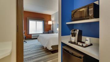 Une chambre d’hôtel équipée d’un lit, d’une fenêtre, d’un bureau avec un micro-ondes, une machine à café et une poubelle.