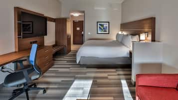 Una habitación de hotel con cama, escritorio, silla, televisor y sofá rojo.