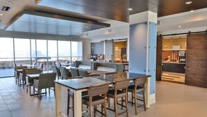 A modern cafe with a large seating area, a coffee bar, and a view of the cityscape. - Holiday Inn Express & Suites Nashville Metrocenter Downtown by IHG (Nashville)