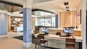A modern hotel lobby with a reception desk, two computer stations, and a view of the parking area. - Holiday Inn Express & Suites Nashville Metrocenter Downtown by IHG (Nashville)