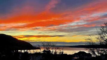 Ein Sonnenuntergang über einem Gewässer, im Hintergrund Hügel.