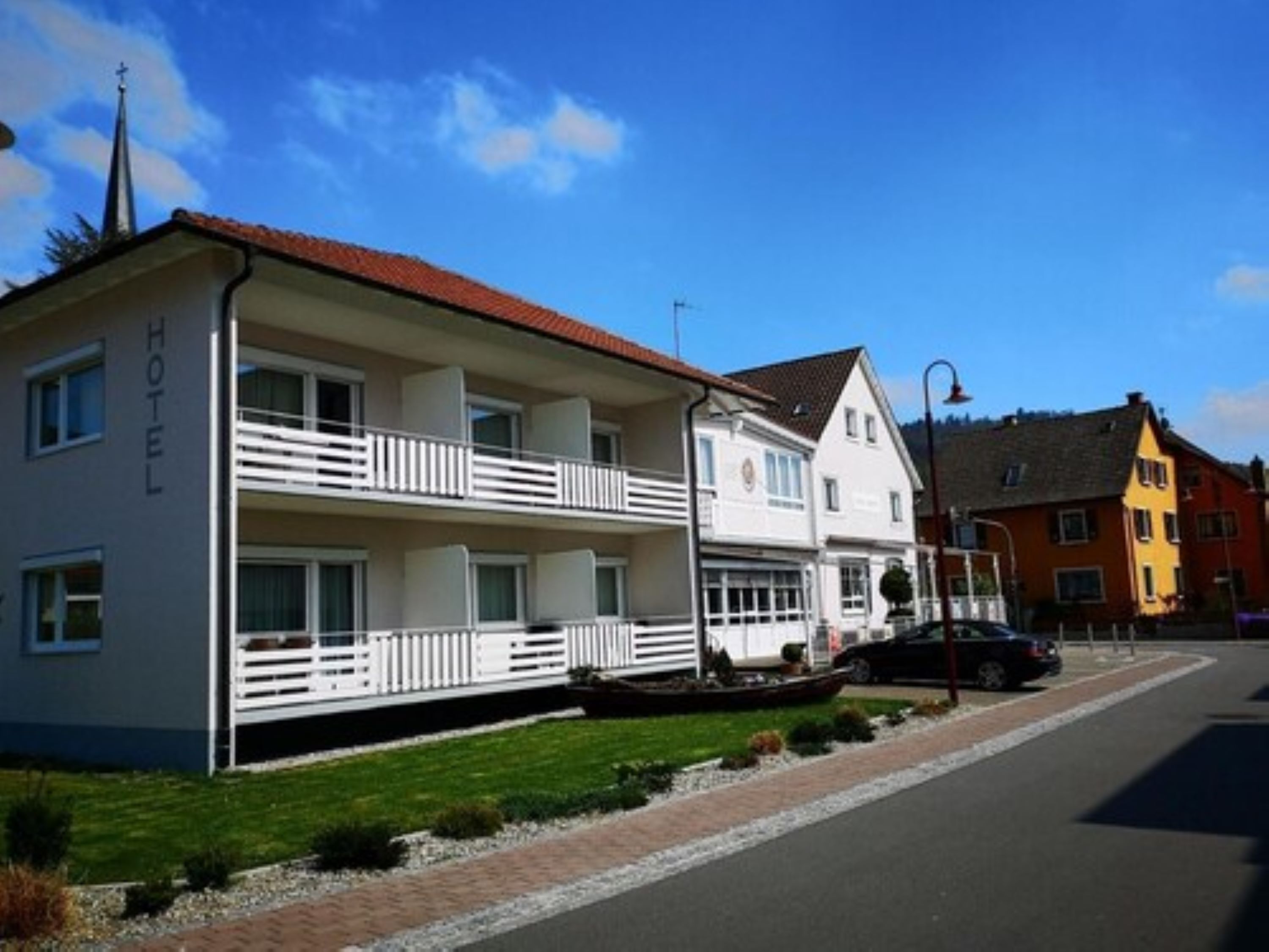Un hotel con fachada blanca, balcones y tejado rojo.
