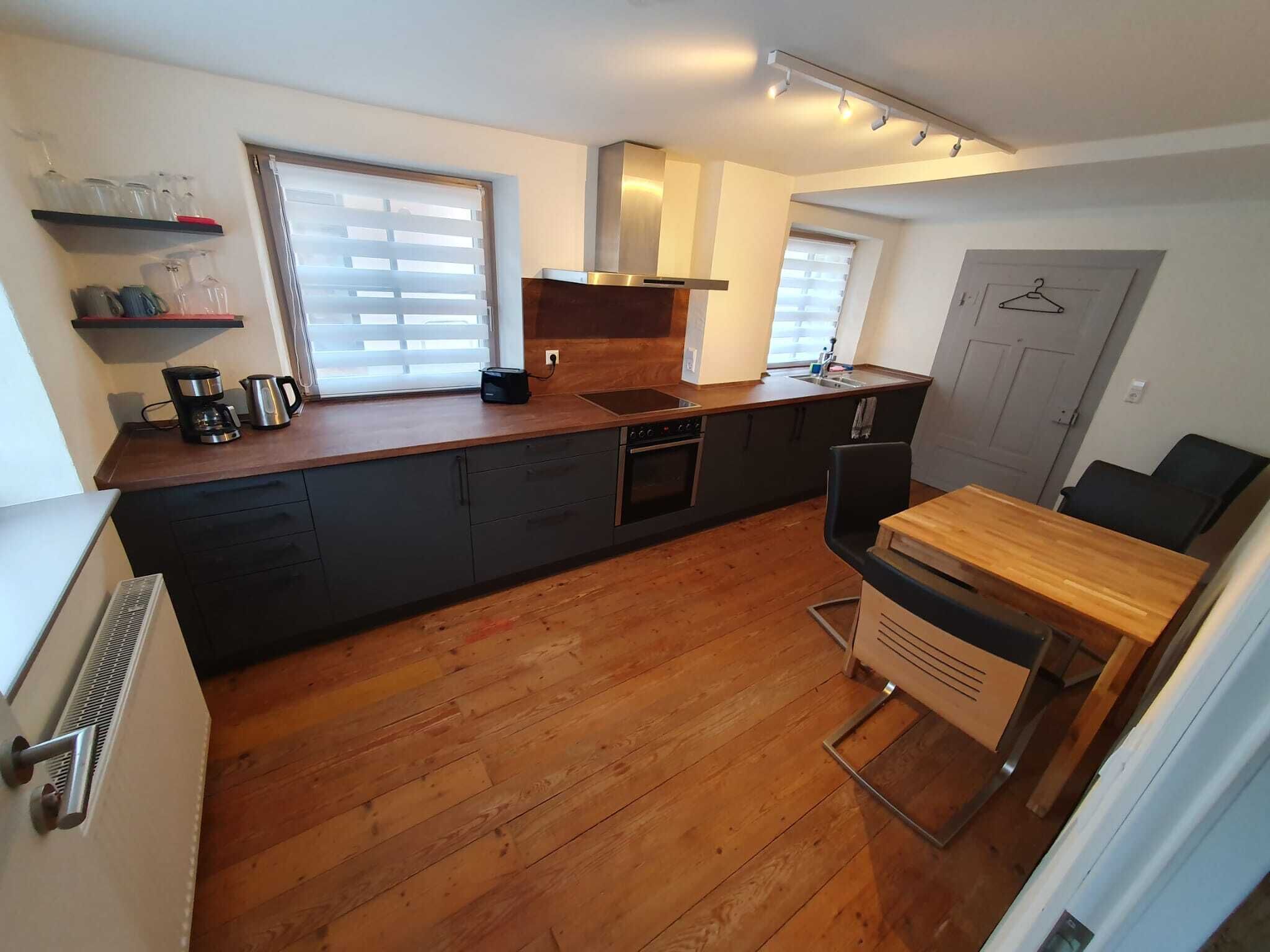 A compact kitchen with a wooden countertop, built-in oven, and a small dining area with a table and chairs.