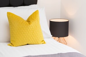 A bed with a white sheet and a yellow honeycomb-patterned pillow. - Sherlock Modern Home by Svelte Living (Birmingham)