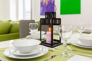 A dining table set with white plates, bowls, and wine glasses, a lit candle, and a black lantern. - Sherlock Modern Home by Svelte Living (Birmingham)