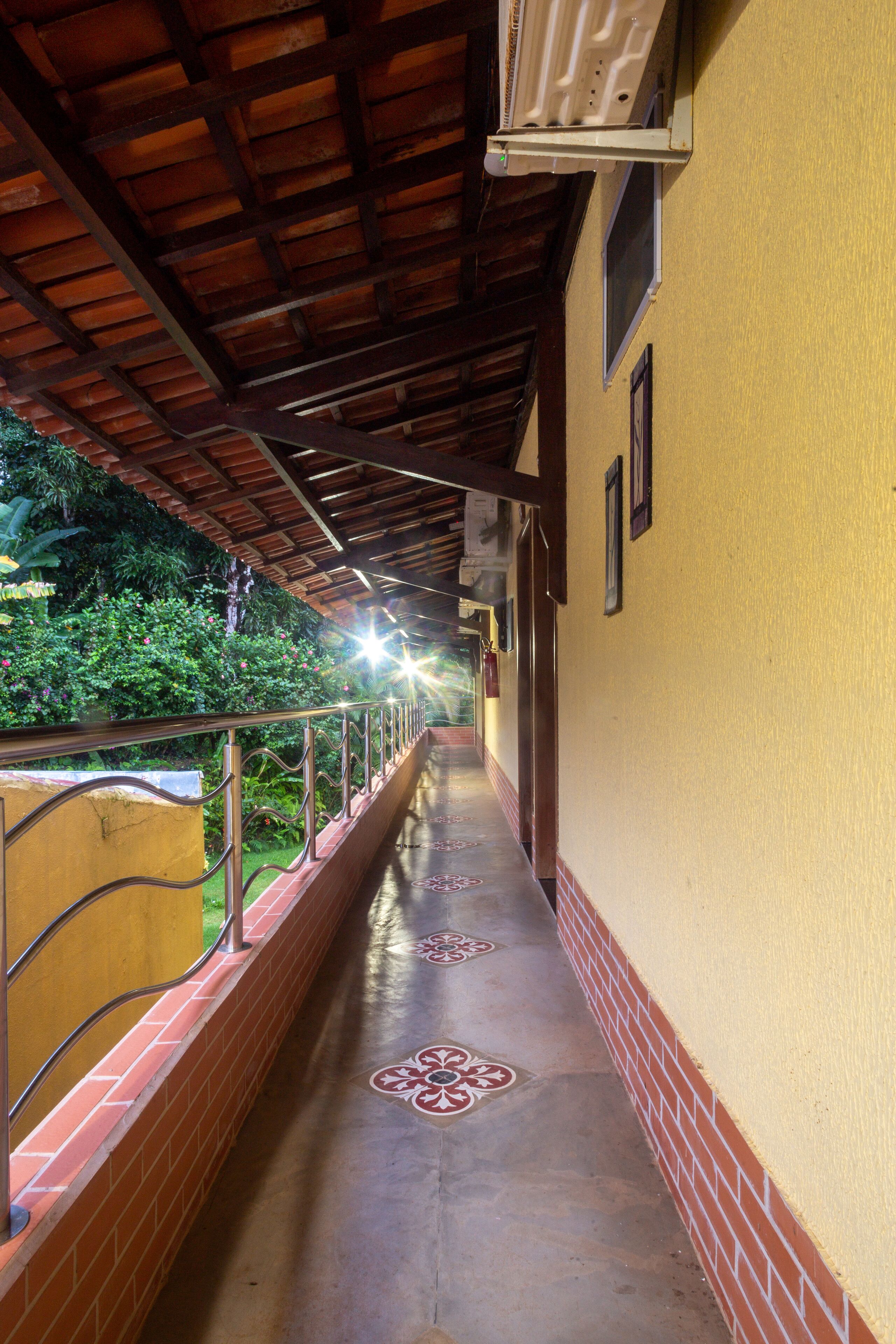 A corridor with a tiled floor, a metal railing, and a wooden ceiling.