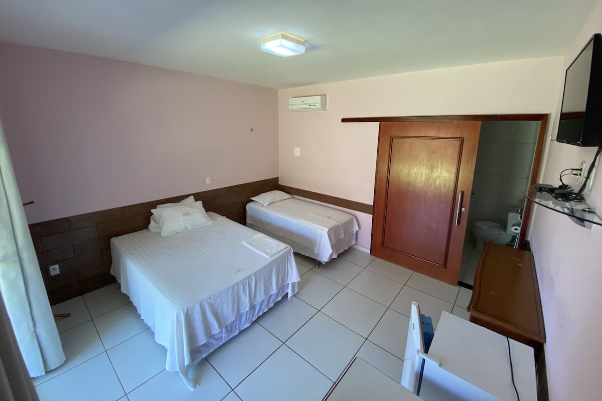 A hotel room with two beds, a wooden door, a small desk, and a television.