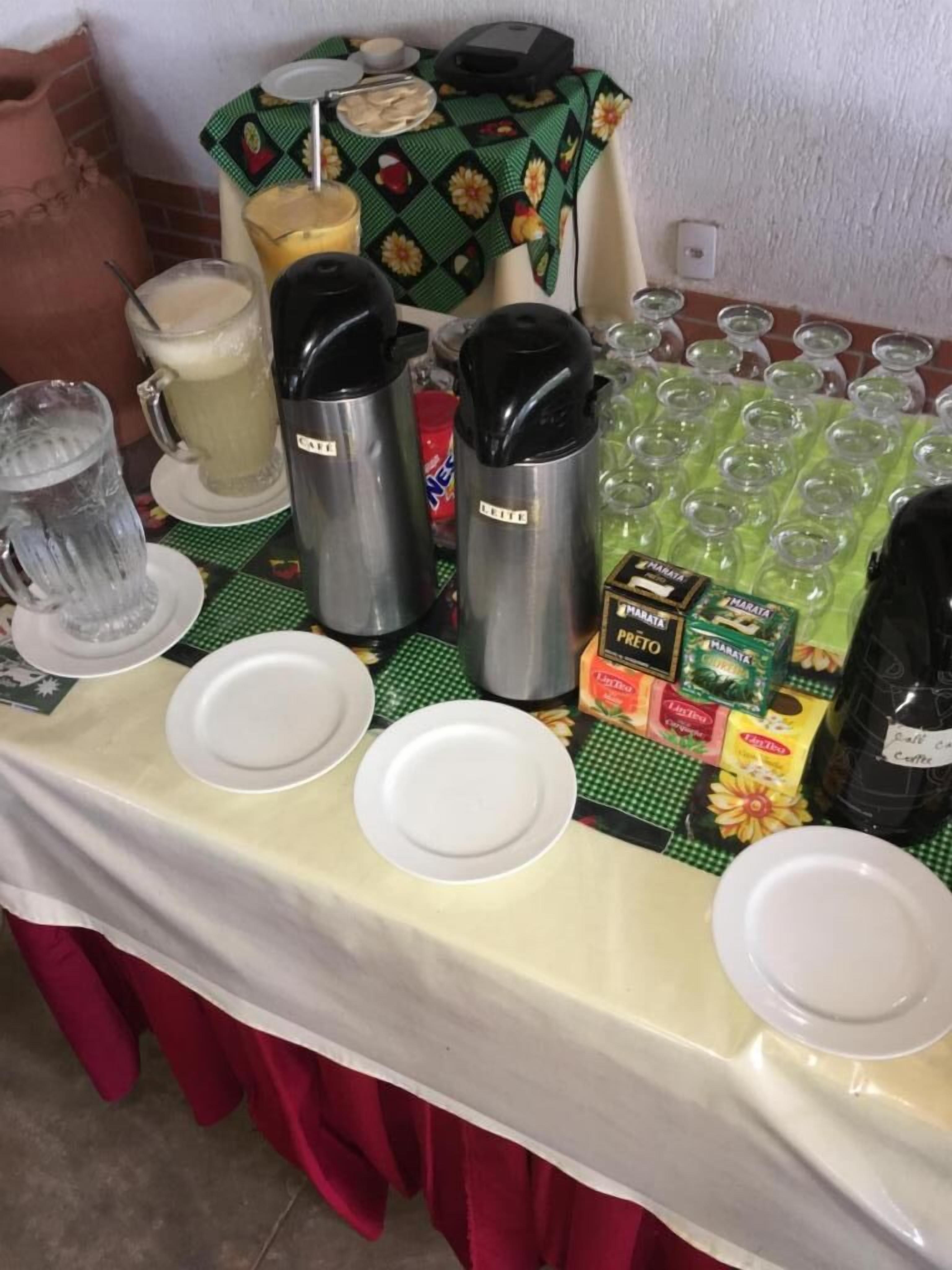A buffet table with various food and drink items, including plates, cups, and containers.