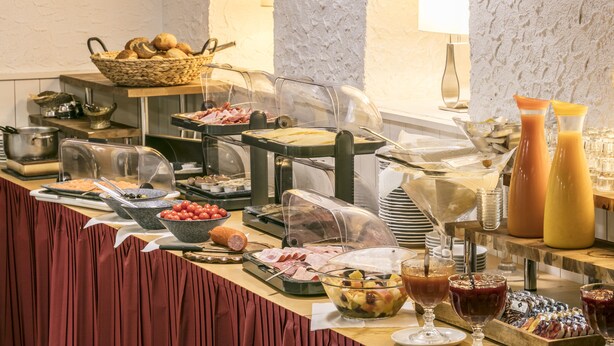 A buffet with various food items, including meats, fruits, and beverages.