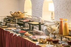 A buffet with various food items, including meats, fruits, and beverages.