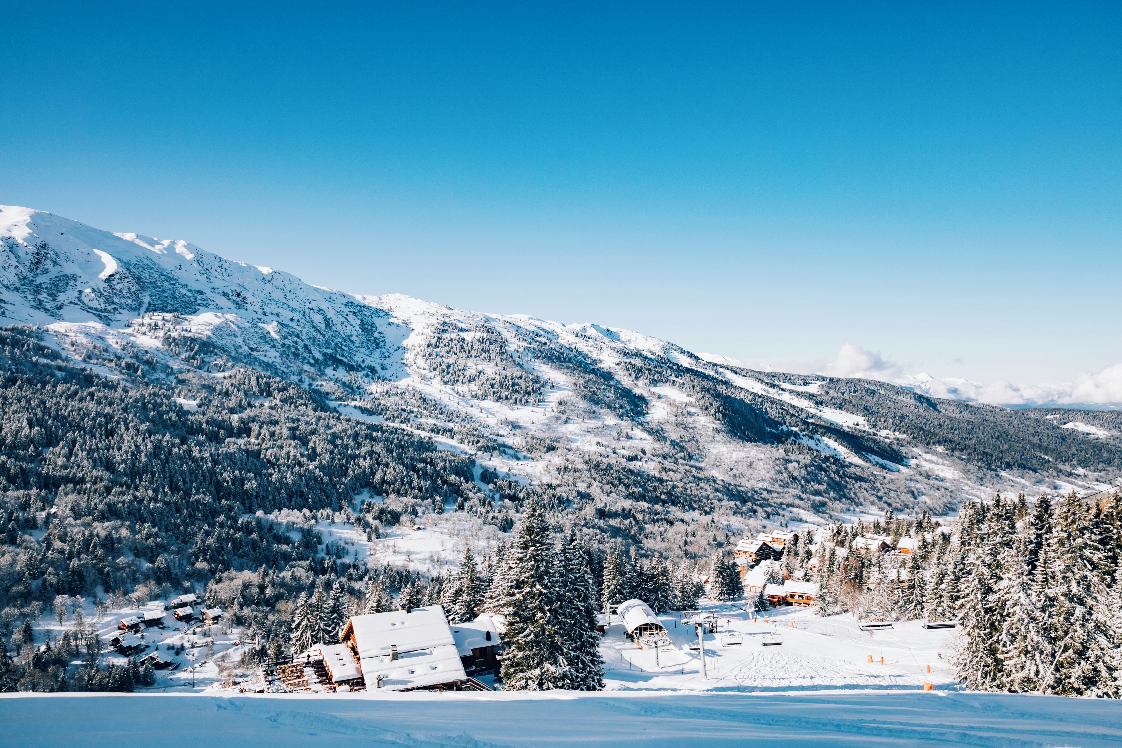 Paisagem montanhosa coberta de neve com chalés e uma estação de esqui.
