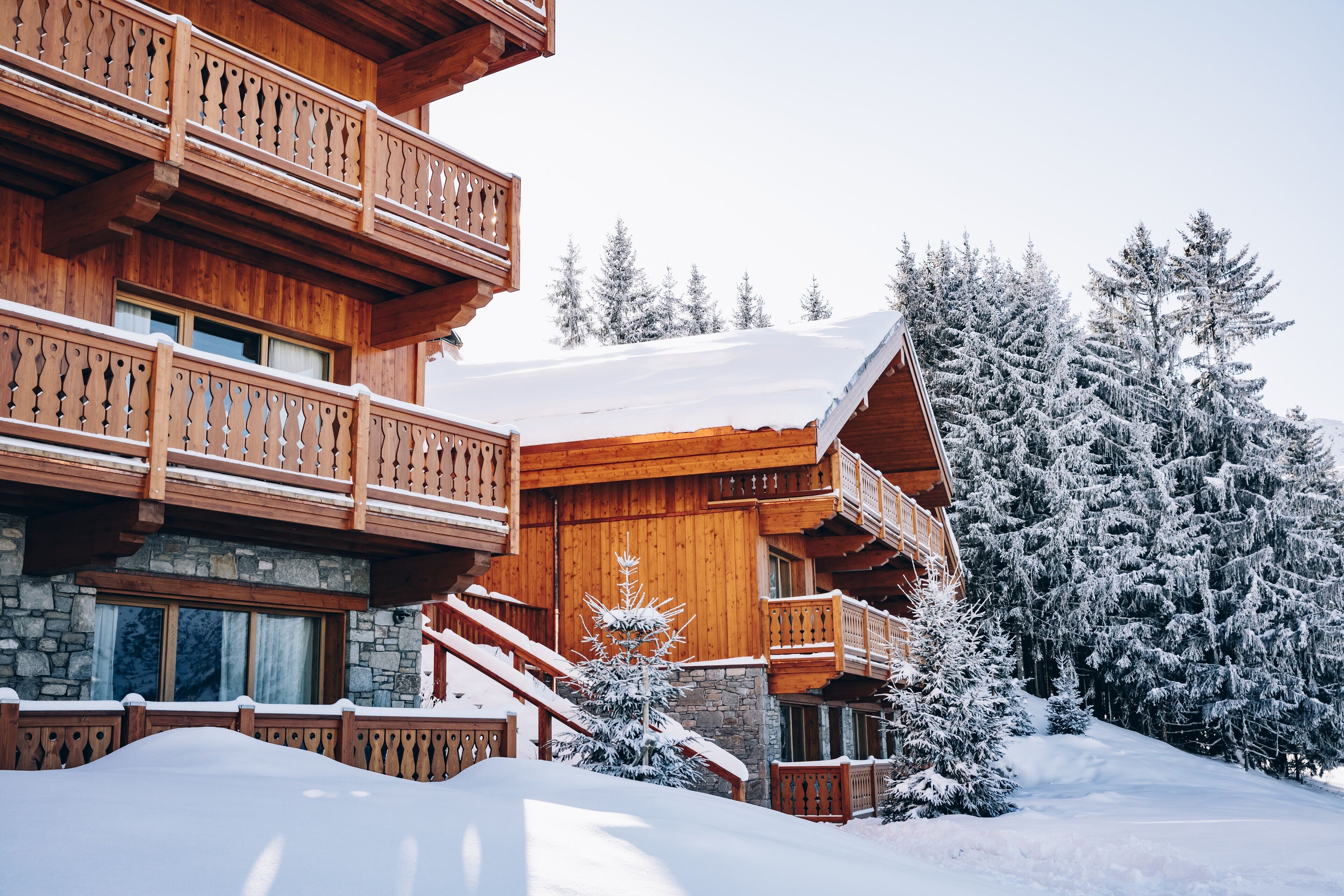 Un chalet en bois doté de plusieurs balcons et reposant sur des fondations en pierre.