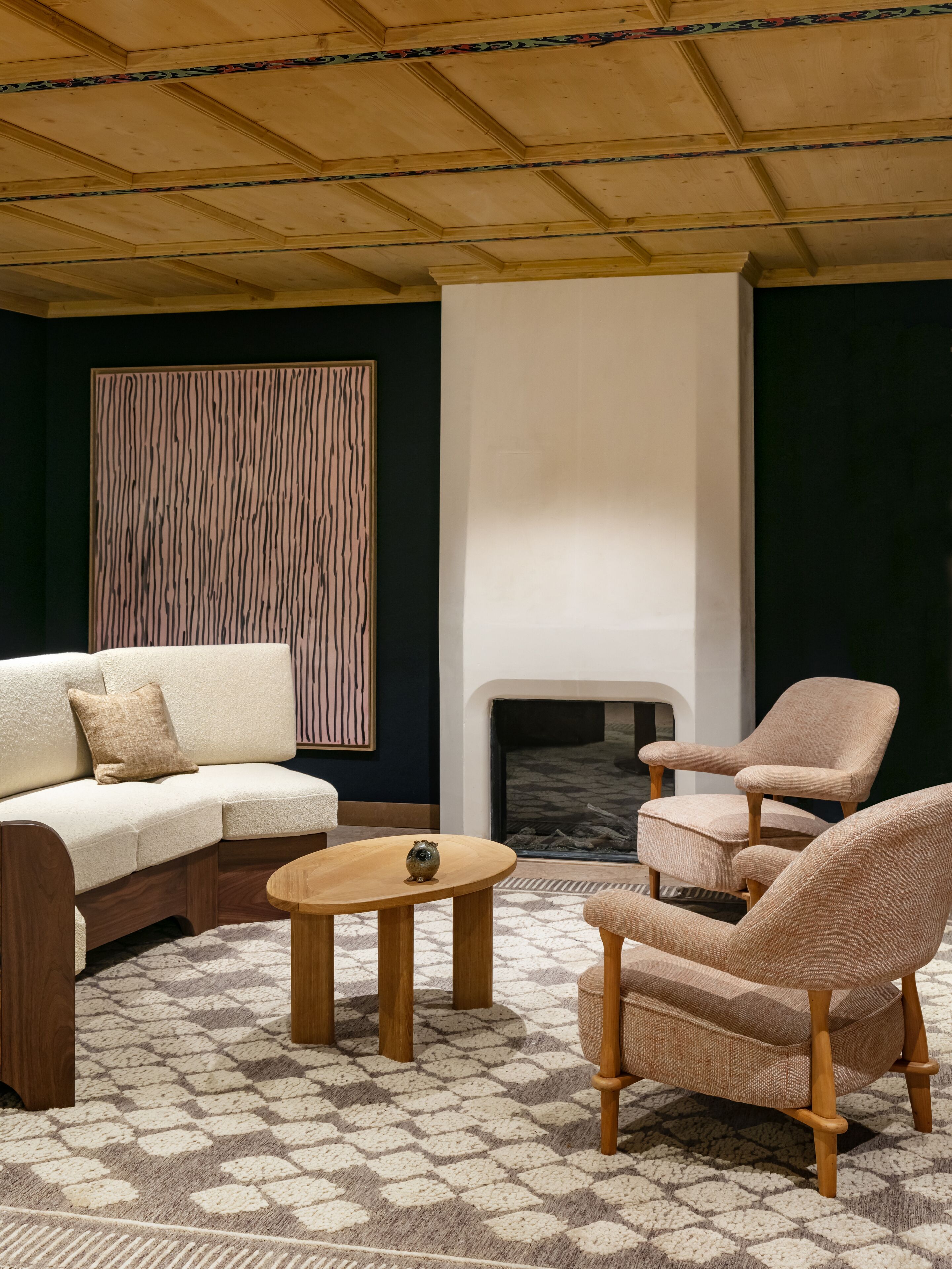 Una sala de estar acogedora con un sofá modular, una mesa redonda y dos sillones. Se ve una chimenea al fondo.