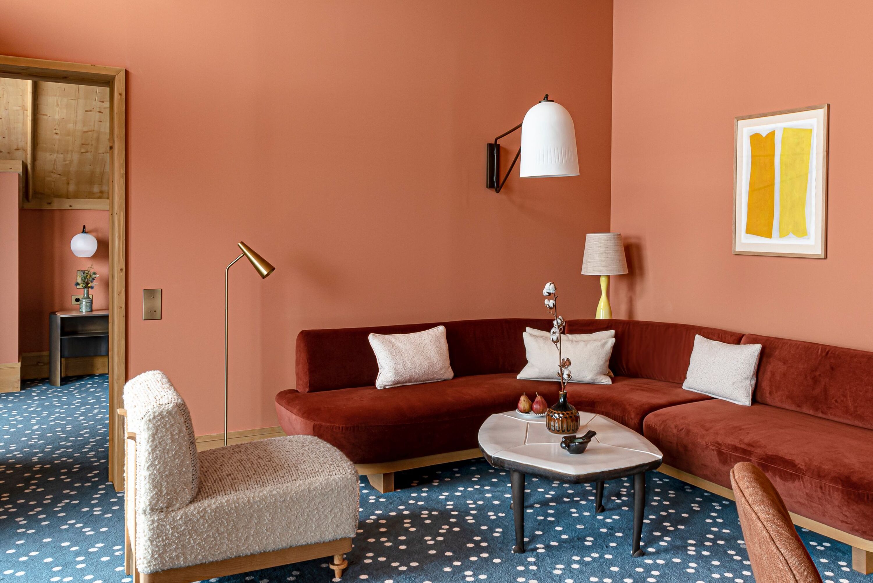 Un salon chaleureux avec un canapé rouge, une table basse ronde et un tapis à pois.