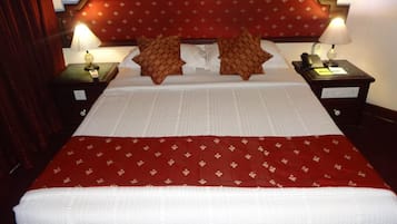 A hotel room with a large bed, two nightstands, a red headboard, and two lamps.