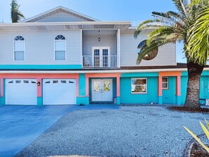 A two-story house with a garage, a balcony, and a palm tree in the front yard. - 244 Flamingo by Distinctive Beach Rentals (Fort Myers Beach)
