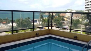A swimming pool with a view of a coastal cityscape through large windows. - Apartment with a view of Morro do Careca. (NATAL)