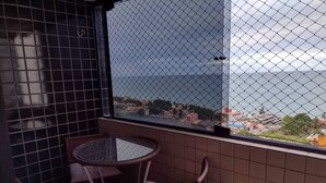 A balcony with a glass partition, wicker chairs, and a small round table. - Apartment with a view of Morro do Careca. (NATAL)