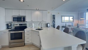 A modern kitchen with white cabinetry, stainless steel appliances, and a large island. - Lovers Key Resort 404 by Distinctive Beach Rentals (Fort Myers Beach)