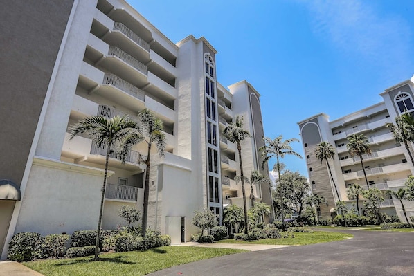 A multi-story hotel with balconies and a central courtyard with palm trees.