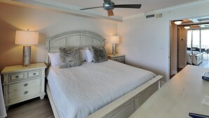 A bedroom with a bed, two bedside tables, a ceiling fan, and a view of the outside. - Lovers Key Resort 403 by Distinctive Beach Rentals (Fort Myers Beach)