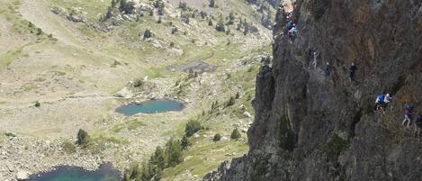 Un paysage montagneux où l’on voit un groupe de personnes en train d’escalader une paroi rocheuse escarpée.