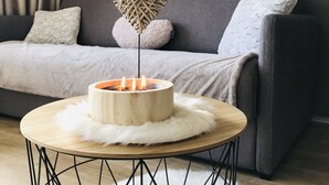 A cozy living room with a grey sofa, a round wooden table with a white fluffy rug, and a wall-mounted sign that reads "COSY". - Charming cabin studio *** 4/5 pers COZY at 50 m from the slopes (CHAMROUSSE)