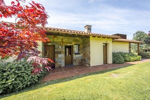 Una casa de dos pisos con techo de tejas, paredes de piedra y un pequeño porche delantero.