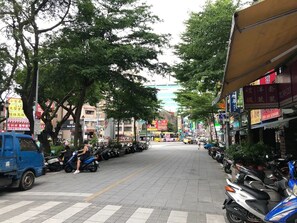 A street lined with parked scooters and a blue truck, with trees and buildings in the background. - DayDay House (Taipei)