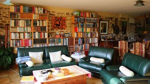 A cozy living room with a green leather sofa, a wooden coffee table, and a bookshelf filled with books. - Ti Er Mad (Kernascleden)