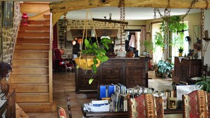 A rustic interior with a wooden staircase, a hanging plant, and a bookshelf filled with books. - Ti Er Mad (Kernascleden)