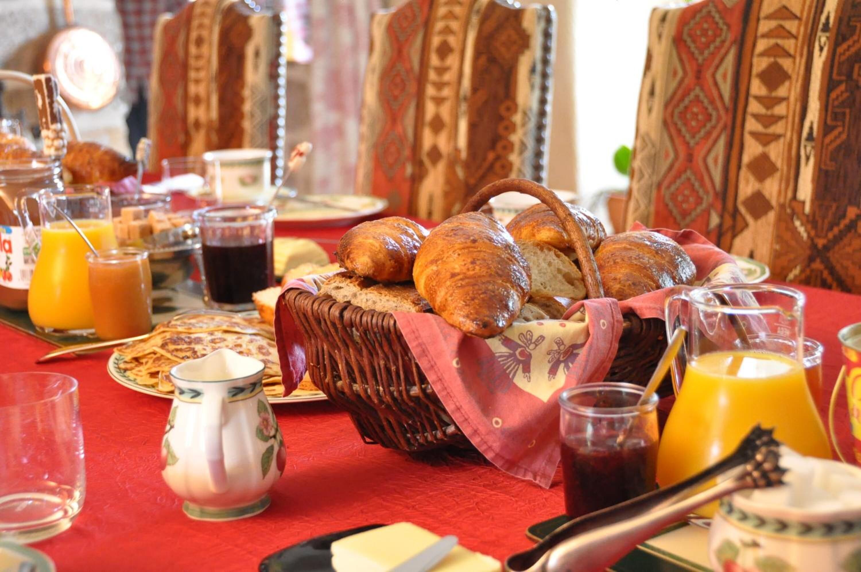 Une table de petit-déjeuner avec du pain, des viennoiseries et des boissons.