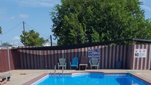 A rectangular swimming pool with a brick border and a metal ladder. - Bayfront Cottages (Rockport)