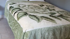 A bed with a floral bedspread, two pillows, and a headboard against a grey wall. - Bayfront Cottages (Rockport)