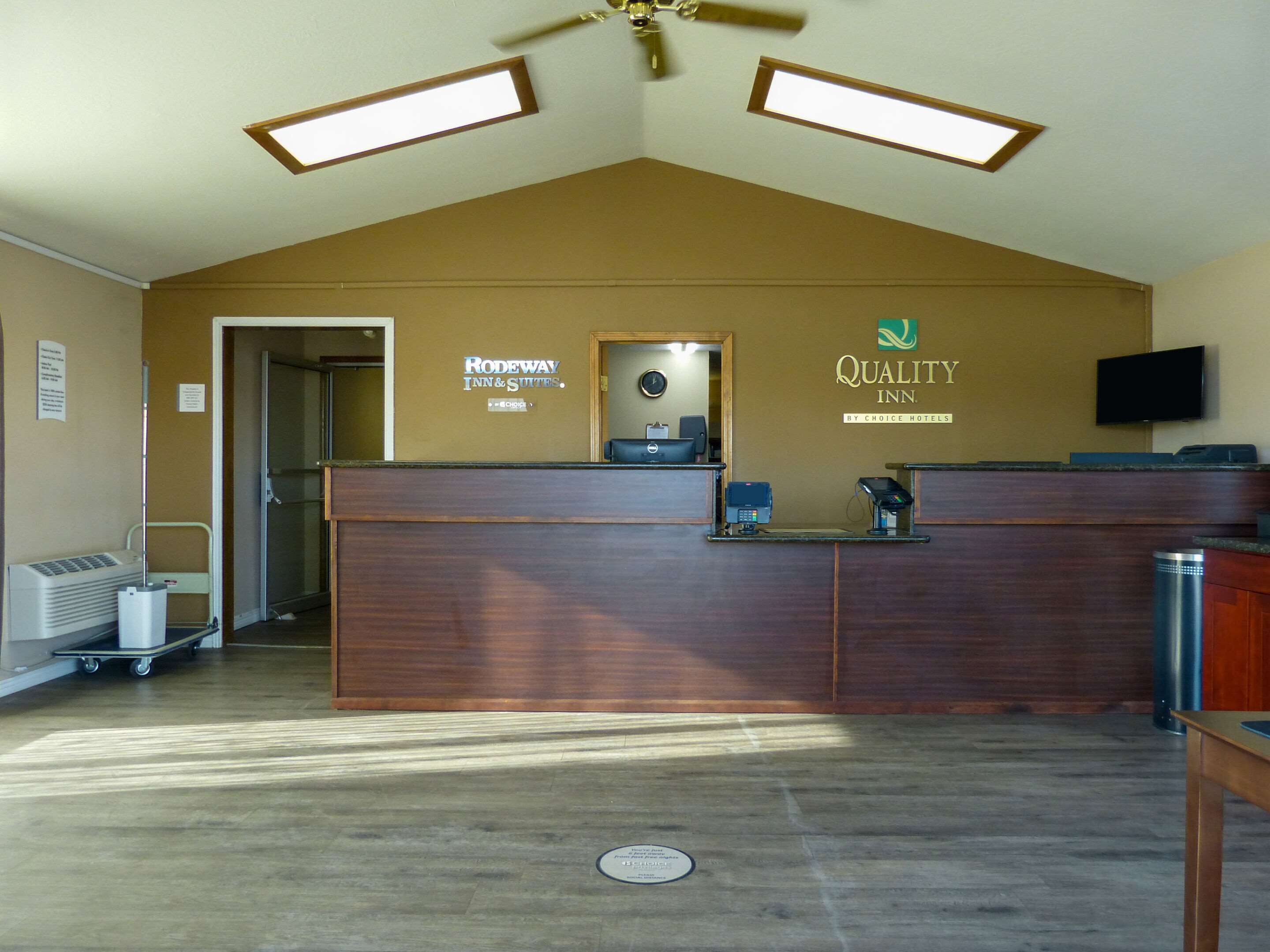 Ein Hotel-Empfangsbereich mit einem Holzbüro, einem Deckenventilator und zwei Hängeleuchten.