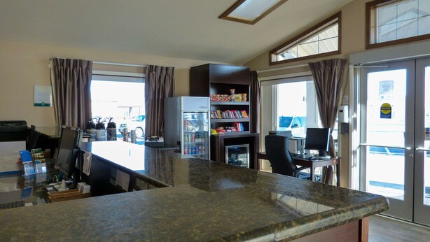 A kitchen with a granite countertop, a refrigerator, and a dining area with a table and chairs. - Rodeway Inn & Suites Ontario (Ontario)