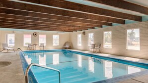 An indoor swimming pool with a wooden ceiling, clear windows, and a few chairs around the pool area. - Rodeway Inn & Suites Ontario (Ontario)