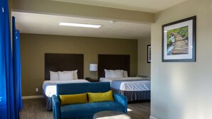 A hotel room with two beds, a blue sofa, a small ottoman, and a framed picture on the wall. - Rodeway Inn & Suites Ontario (Ontario)