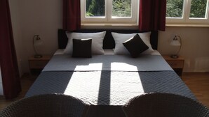 Un lit recouvert d’une courtepointe matelassée, deux tables de chevet avec des lampes et une fenêtre avec des rideaux.