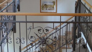 Un escalier orné de rampes de fer forgé noires, d’une main courante en bois et d’un lustre.