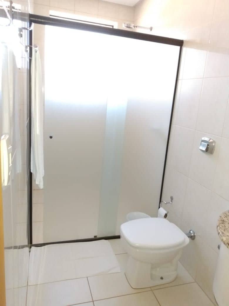 Un baño con cabina de ducha de vidrio, un inodoro y un perchero para toallas.